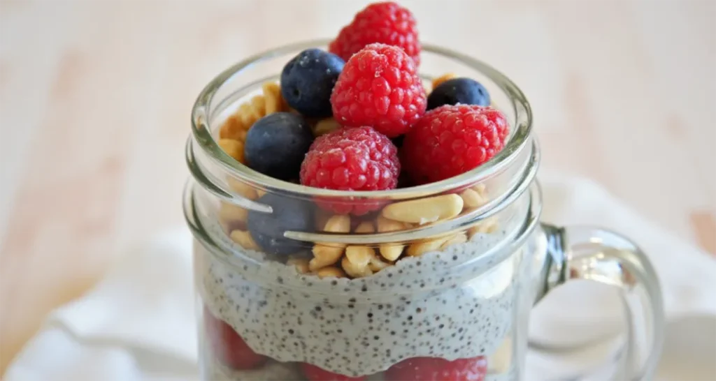 Chia pudding in a jar topped with fresh berries, nuts, and a drizzle of honey