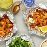 Shrimp Boil Foil Packets paired with a crisp green salad, crusty bread, and a pitcher of iced lemonade