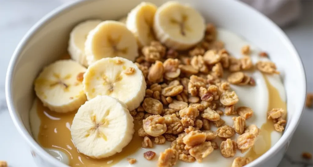 Greek yogurt bowl topped with almond butter, granola, and sliced bananas for a healthy camping breakfast