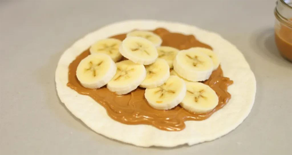 Adding banana slices on top of the peanut butter