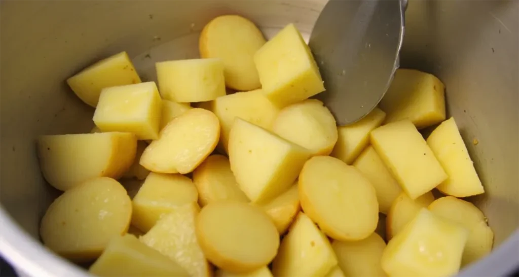 Cubed potatoes being tossed with butter and garlic in a bowl