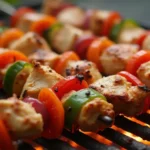 Grilled chicken skewers with charred edges over glowing coals.