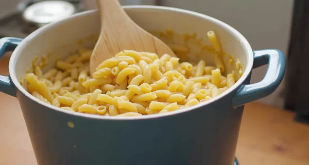 One-pot pasta with marinara sauce and vegetables on a portable camping stove.