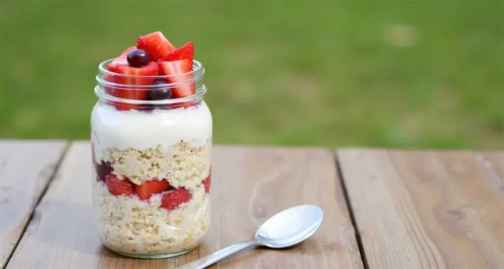 Overnight oats with fruit in a mason jar on a picnic table at a campsite.