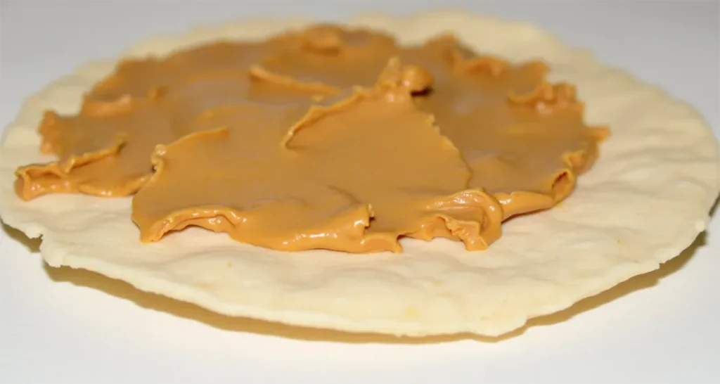 Spreading peanut butter on a tortilla as the base layer