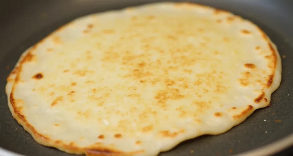 Cooking a campfire quesadilla in a cast-iron skillet.